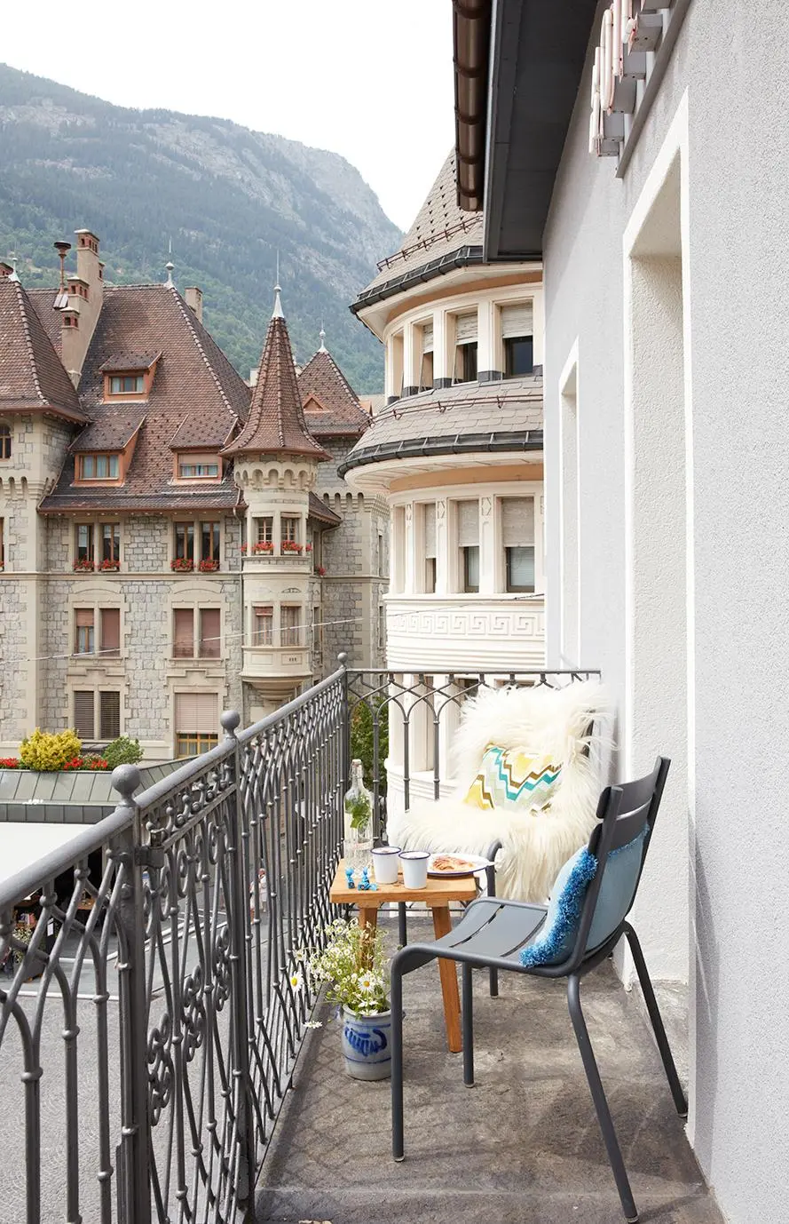 Hotel balcony with Fermob chairs and views of historic architecture and the Swiss Alps