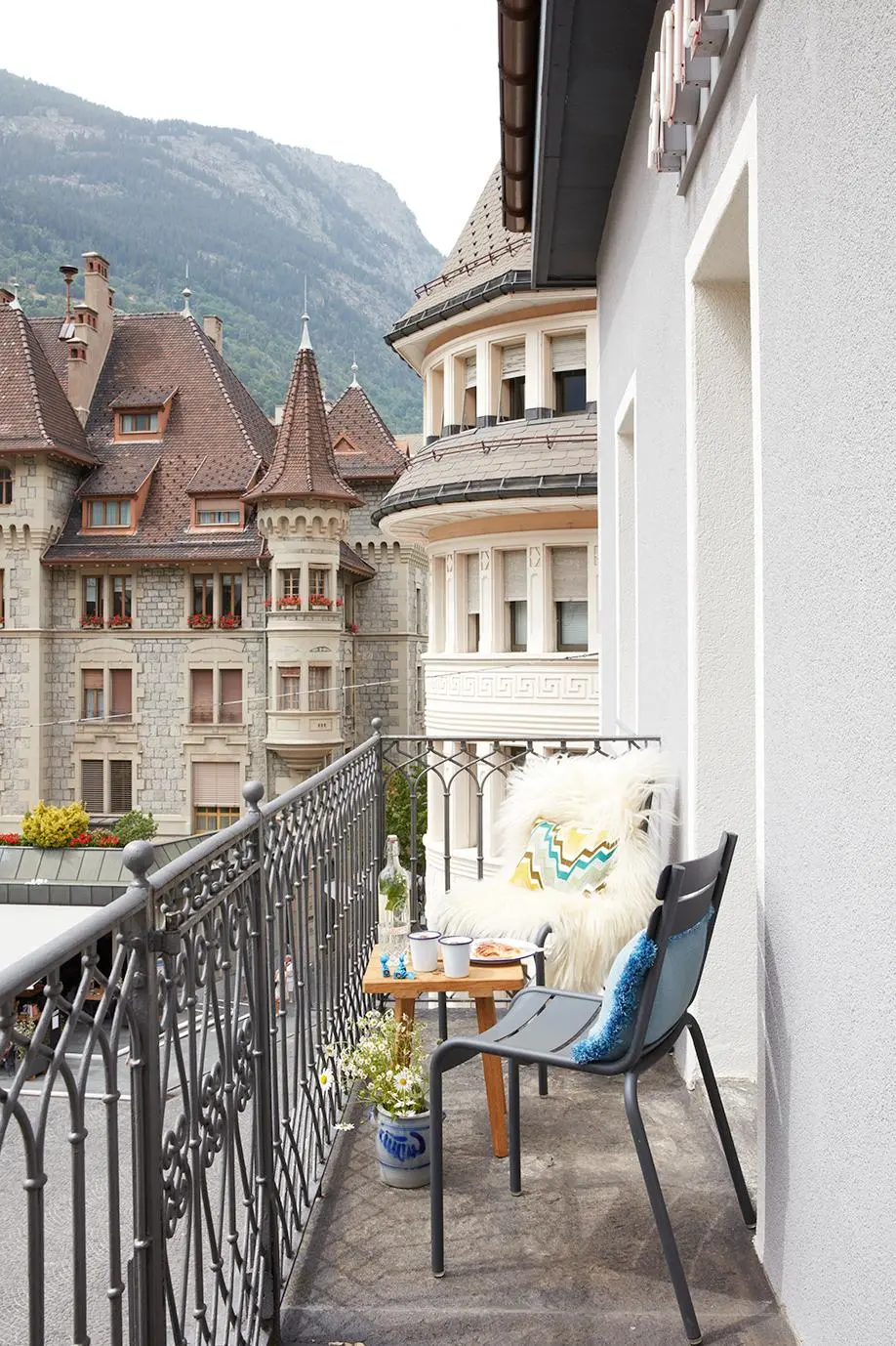 Hotel balcony with Fermob chairs and views of historic architecture and the Swiss Alps