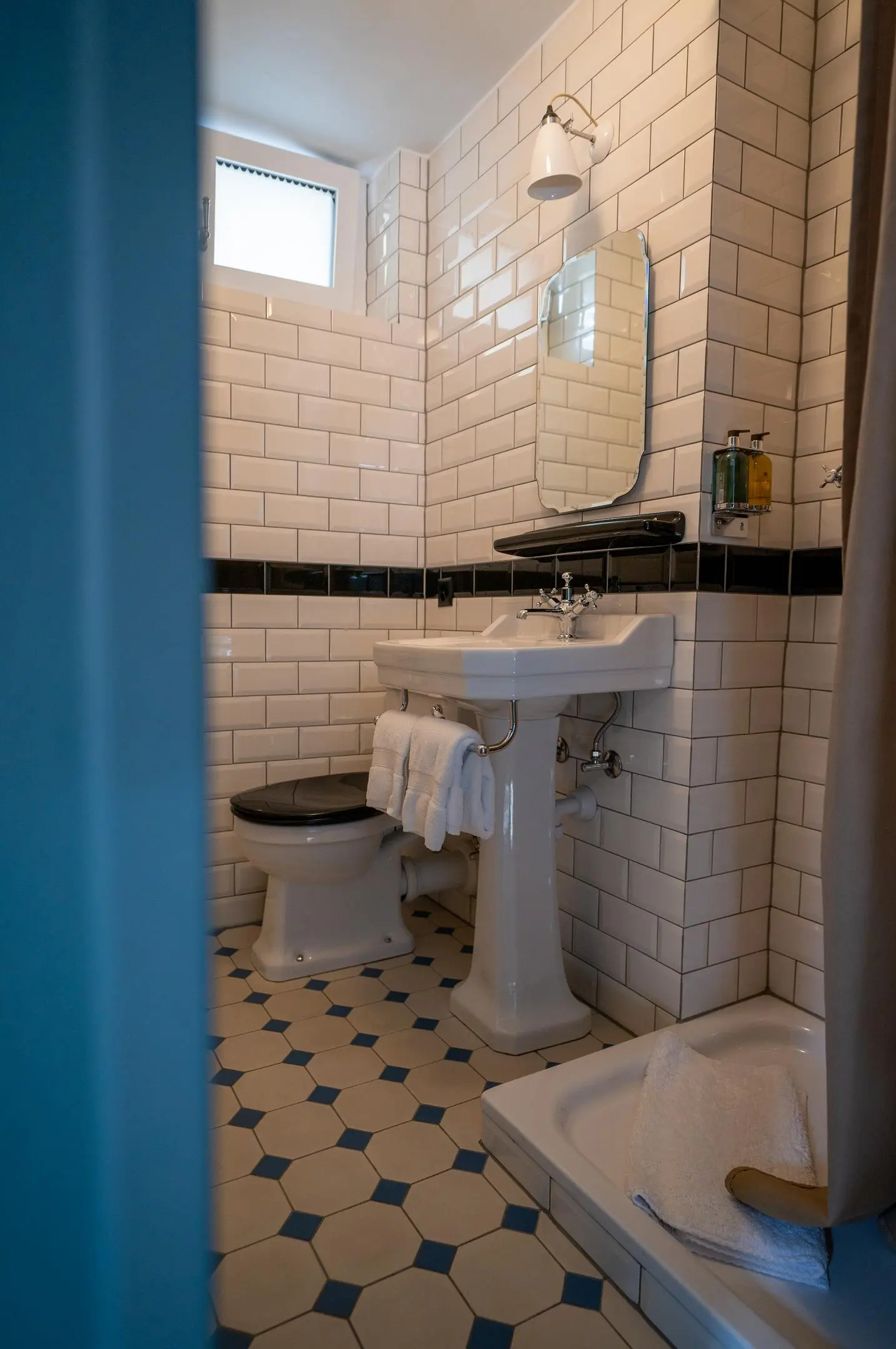 Hotelbadezimmer im englischen Stil mit weißen Metrofliesen und historischen Sanitärelementen