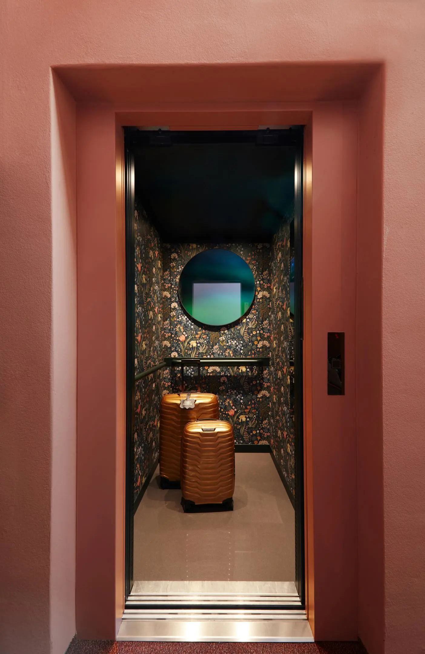 Hotel lift with decorative Boråstapeter wallpaper and gold-coloured luggage